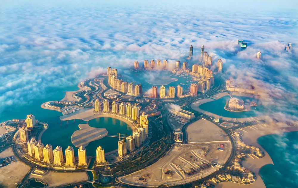 Aerial view through clouds over Pearl-Qatar island to indicate why you should visit Qatar