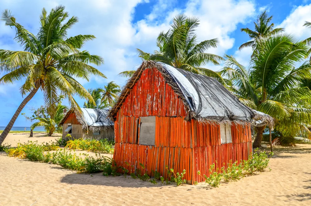 Traditional red Tongan house on Uoleva Island with palm trees around it to indicate the cheapest time to visit Tonga