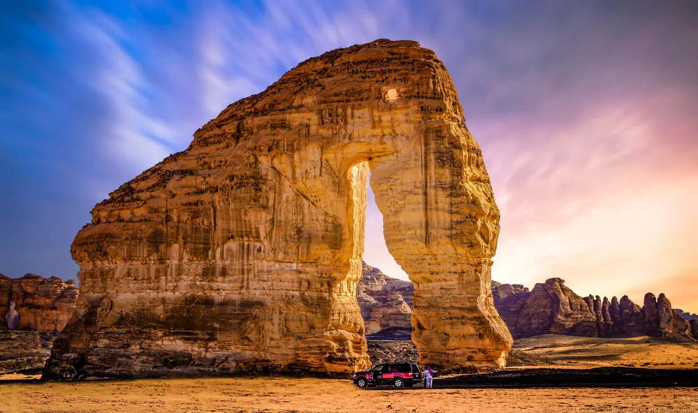 Elephant Rock at sunset with colorful sky as a car passes in front for a frequently asked questions section on the best time to visit Saudi Arabia 