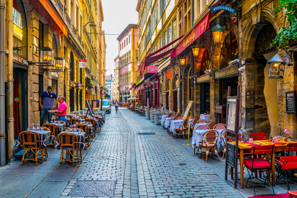 Lone person walks through a narrow alleyway in the restaurant district in one of the best parts of Lyon to stay in when visiting