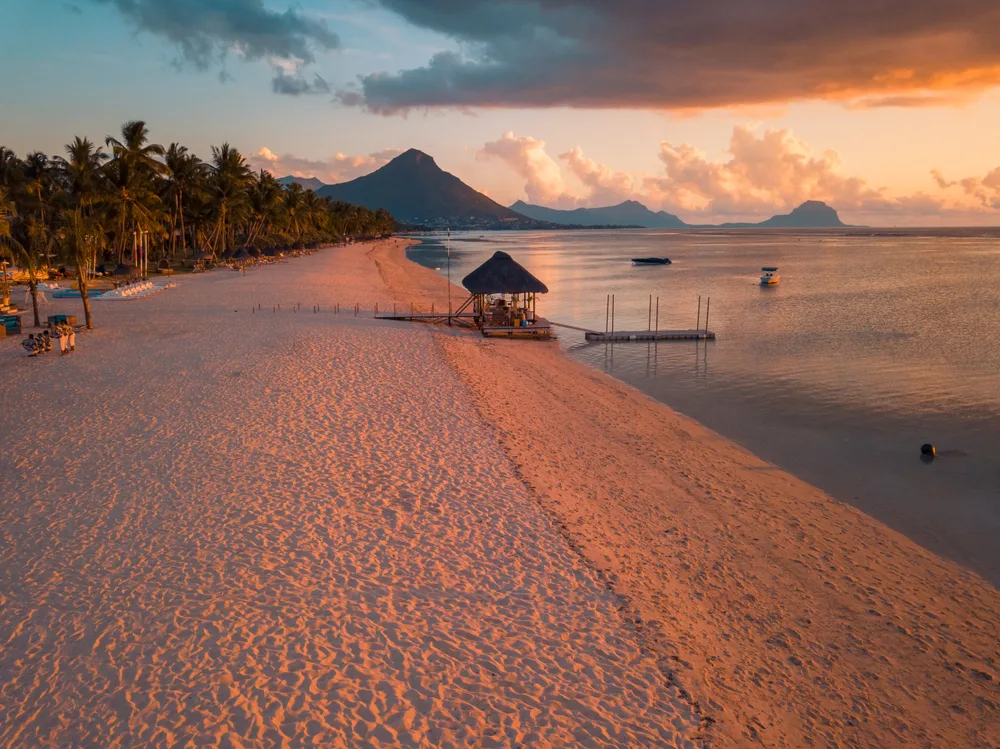 Idyllic view of the expansive beach along Flic and Flac in Mauritius with the sun setting over the ocean