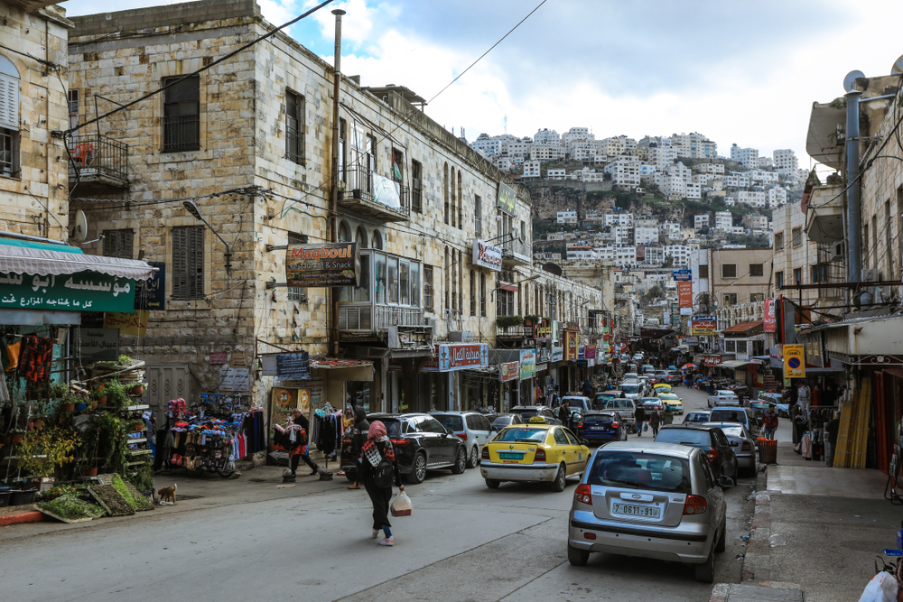 Photo of people walking along in Nablus Palestine with huts sprinkled throughout the hillside
