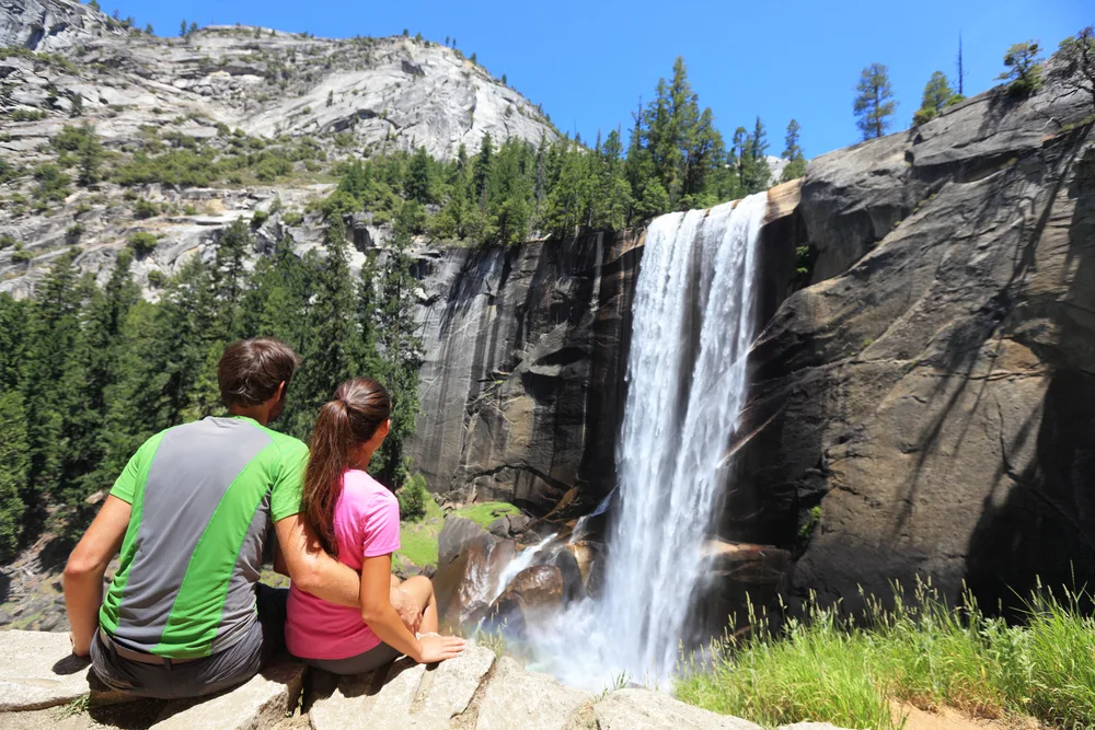 Young and attractive hikers overlooking the Vernal Falls in Yosemite for a piece on whether or not the park is safe to visit