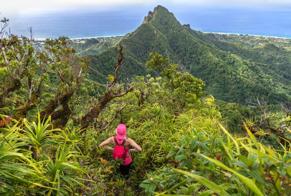 For a guide to whether the Cook Islands are safe to visit, a woman with her hands on her hips pictured hiking the volcano in Rarotonga