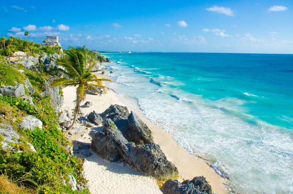 Gorgeous beach in Tulum with the ruins overlooking the ocean with a rocky coastline below