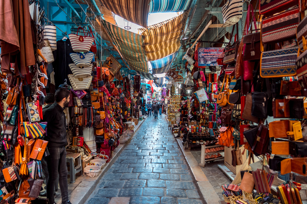 Colorful souks market with goods hanging up along an alley during the overall best time to visit Tunisia