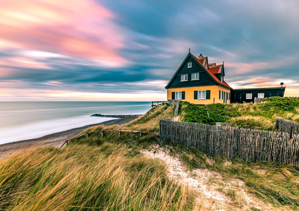 Gorgeous yellow and brown house on the ocean in North Jutland for a piece on the overall best time to visit Scandinavia