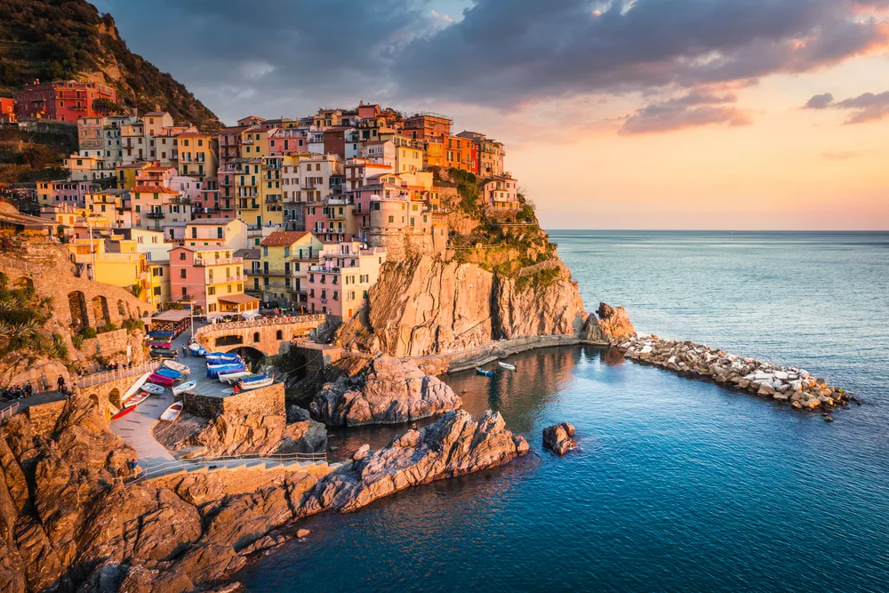 Aerial view of Manarola with houses along the cliffs at sunset during the cheapest time to visit Cinque Terre