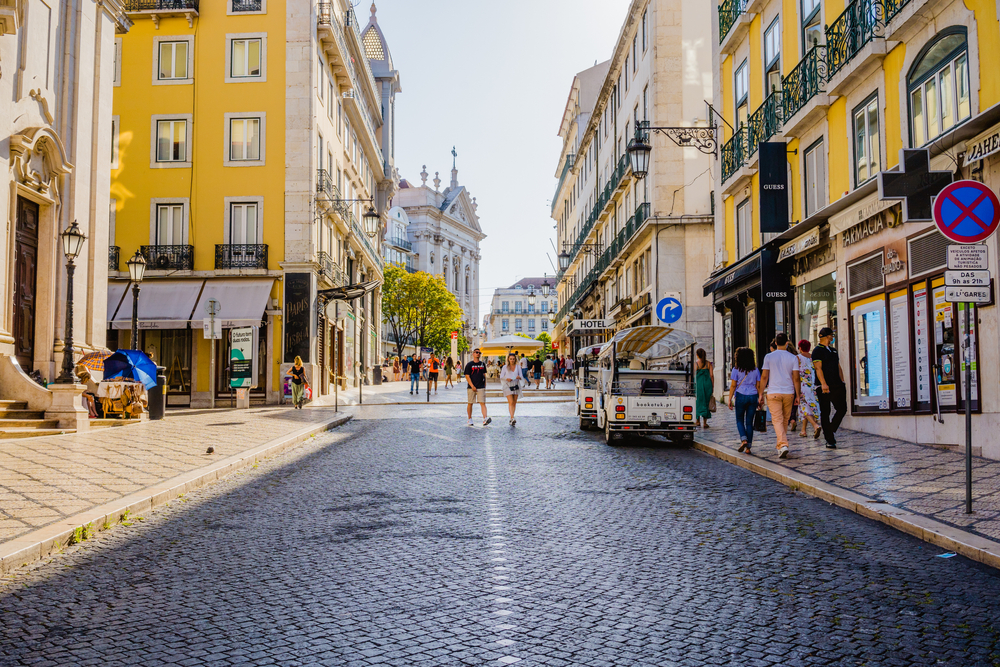 People walking along the cobblestone street of Chiado in Lisbon, one of the beset areas to stay when visiting