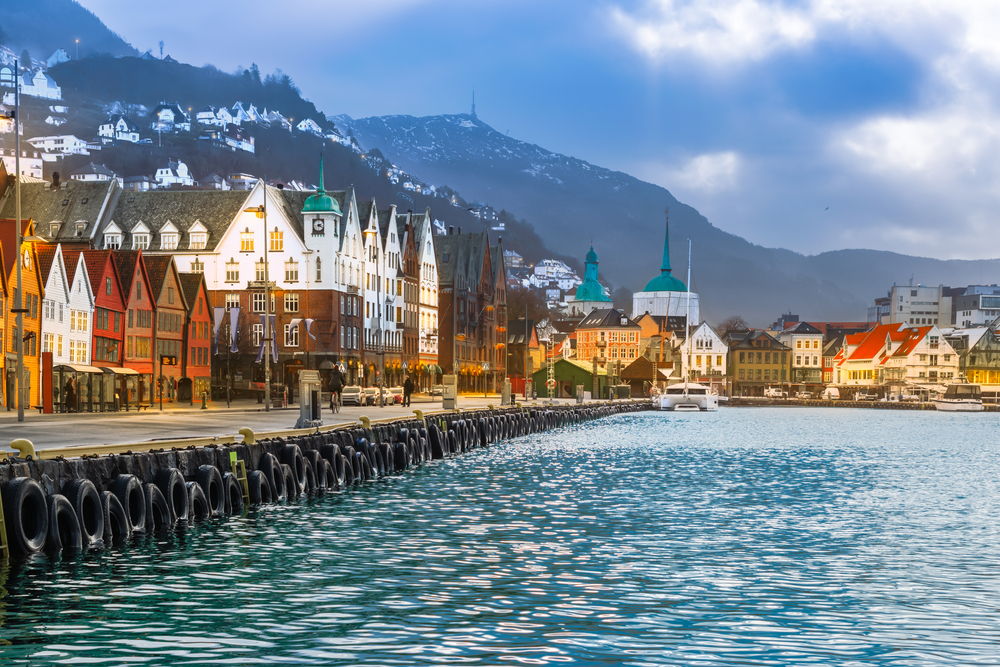 For a piece on whether Norway is safe to travel to, a photo of the historic Bryggen Harbor in Bergen Norway, taken from the water, with ice on the water