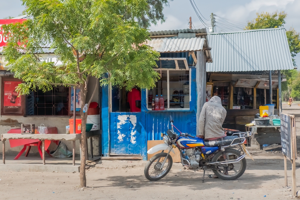 Blue shop in back of a motorcycle pictured by a roadside market in Tanzania
