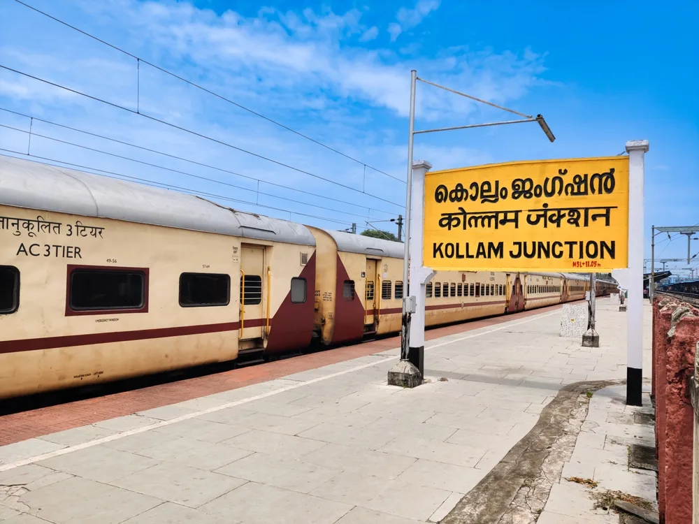 Old train next to the yellow Kollam sign pictured for a section on the least safe places to visit in Kerala