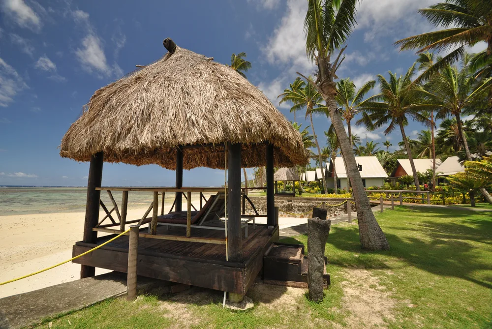 Small huts on the white-sand beach of the Coral Coast pictured for a piece titled Where to Stay in Fiji