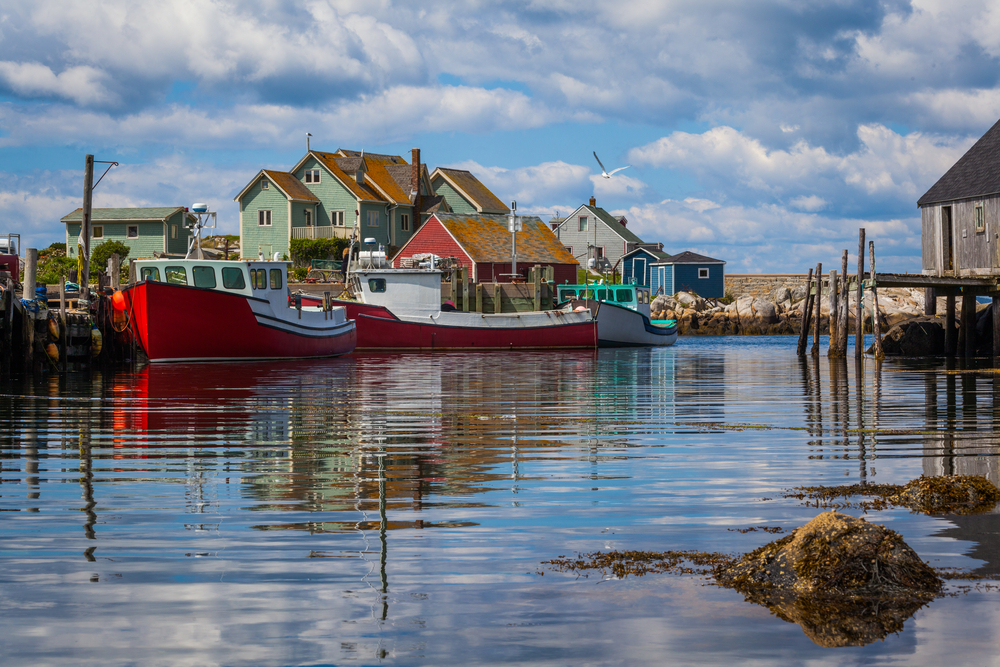 Photo taken from the decks of the homes on Peggy's Cove with small fishing boats floating on the water for a piece titled What Is the Best Time to Visit Nova Scotia