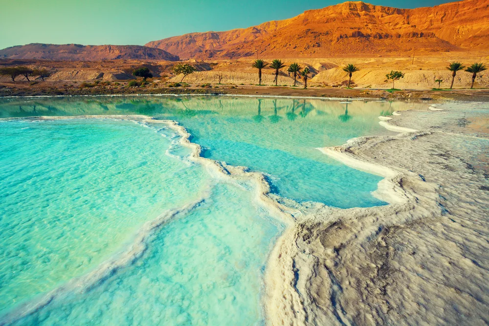 Salty shoreline of the Dead Sea with shallow teal water pools