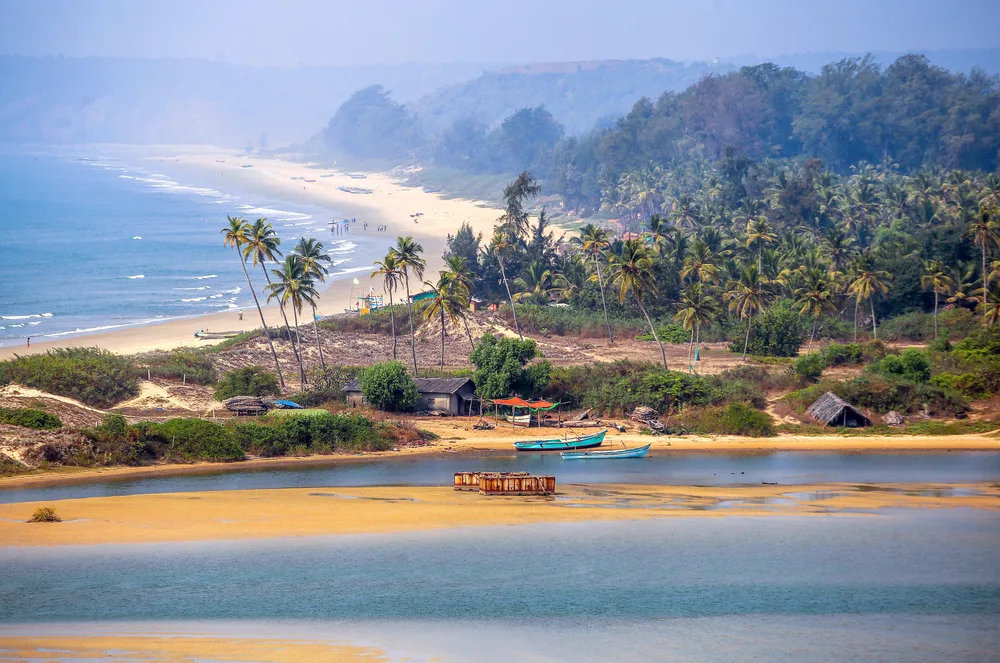 Picturesque image of a beach that is hazy with boats in front of the water in wonderful Goa for a piece on whether or not the city is safe to visit