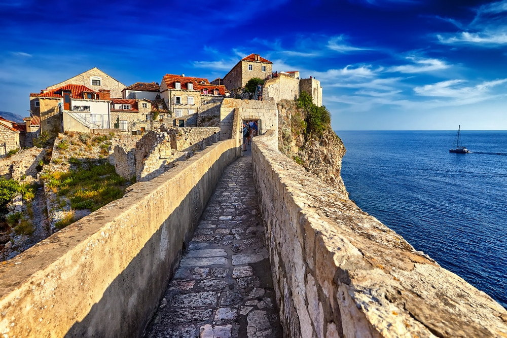 Walkway along the fortress walls of the Old City during the cheapest time to visit Dubrovnik from November to March with blue skies overhead