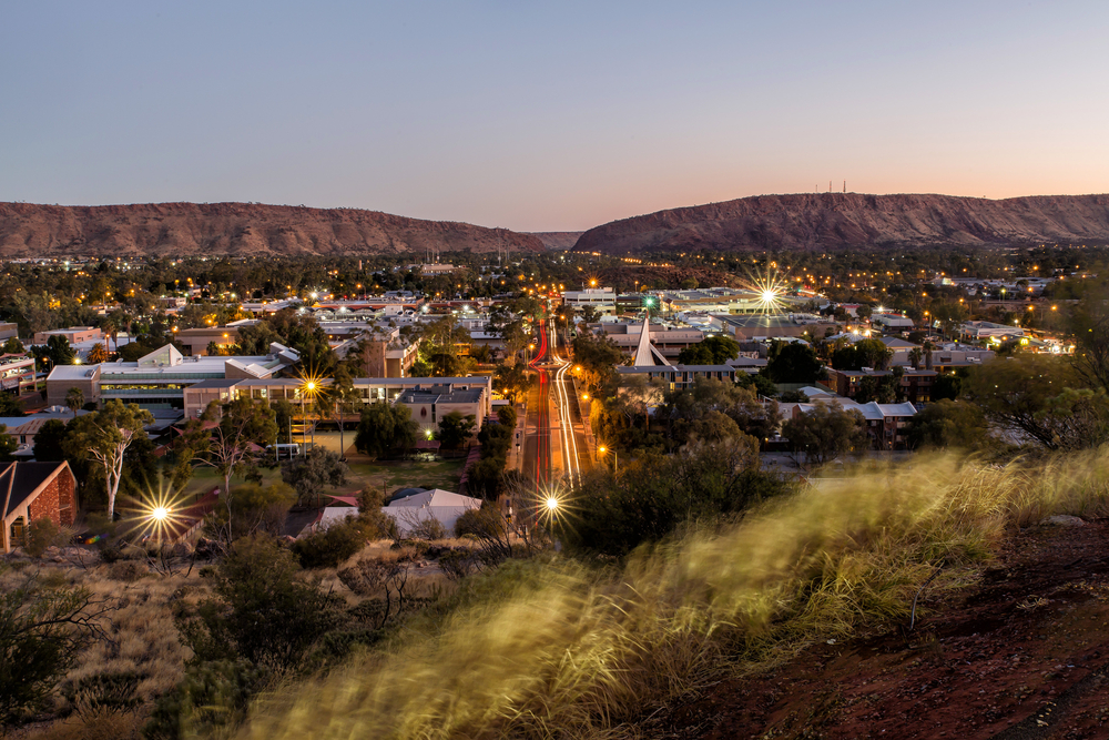 Night hilltop view of Alice Springs, one of the areas in Australia to avoid, seen with lights below on a clear day