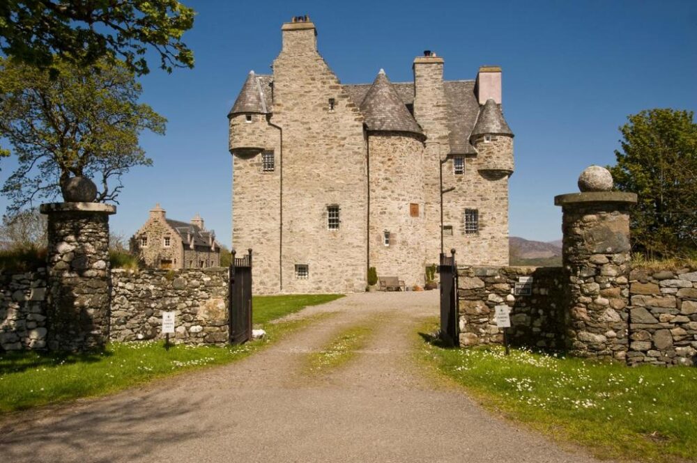 Barcaldine Castle hotel, one of the best castle hotels in Scotland, seen from the driving path leading between two stone gates up to the front