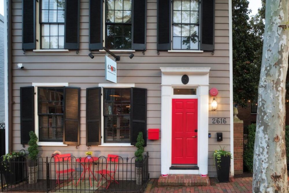 Exterior of one of the best boutique hotels in Washington DC, The Poppy Georgetown Guesthouse and Gardens, pictured with little red chairs outside of the old home