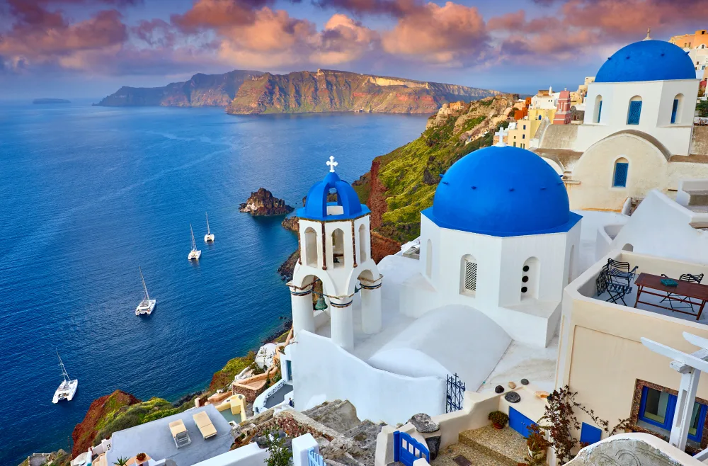 View of Fira, Santorini in Greece with famous white and blue buildings on the coast at sunset, shown as one of the best places to go for your birthday
