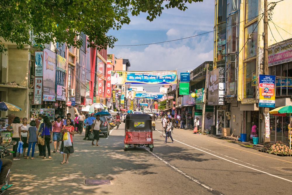Busy and crowded street in Gale, for a piece on is Sri Lanka safe to visit, with countless locals and small motor vehicles making their way down the winding street between old-looking buildings with colorful signs on either side