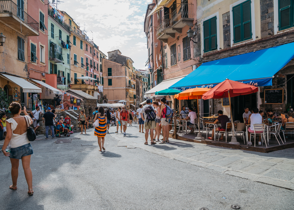 People walking around an open-air market on a cloudy day in the seaside village of Vernazza