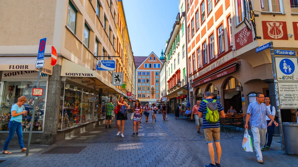 People walking around the tourist area of Alstadt, one of the best areas to stay in Munich, on a clear day with few people on the street