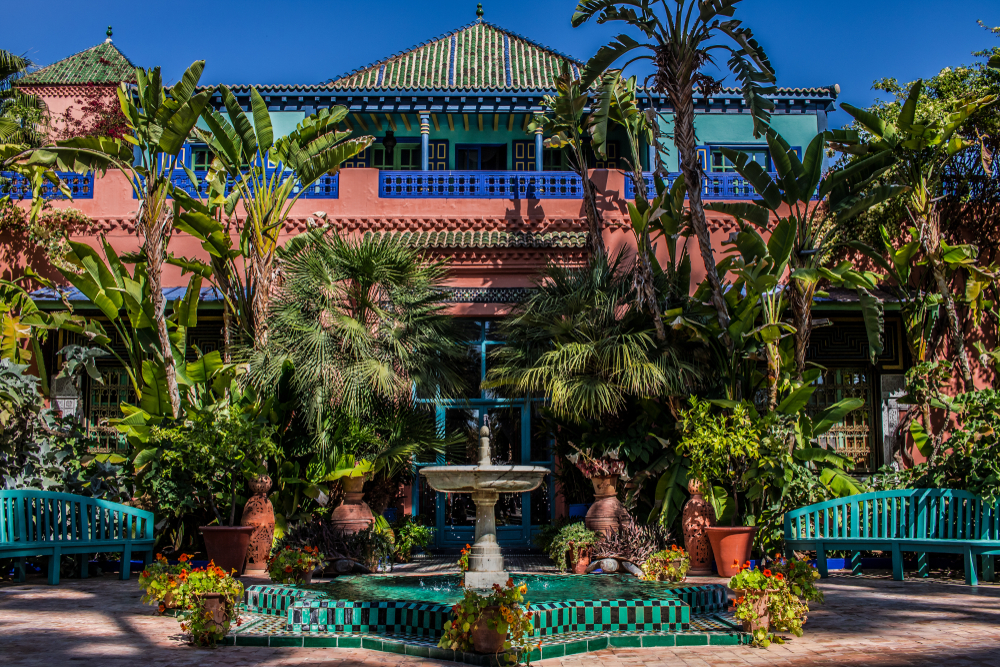Exterior view of the villa of Yves Saint Laurent or Jardin Majorelle gardens with lush plants for a frequently asked questions section on the best riads in Marrakech