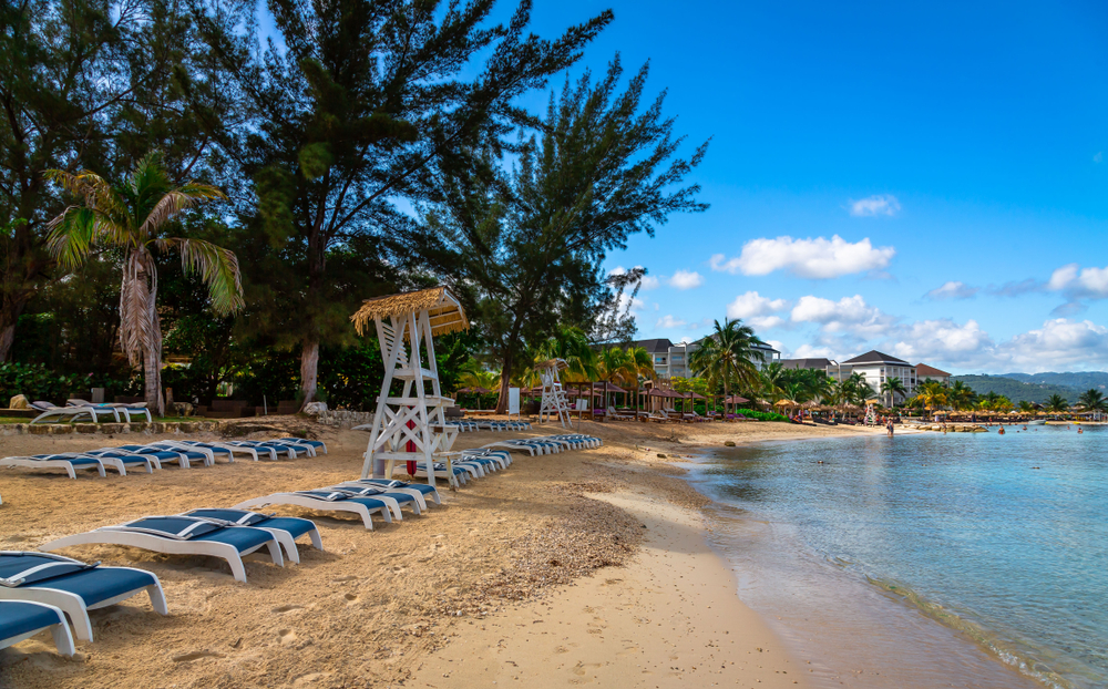 Sun chairs and lifeguard stations on a tan sand beach in Montego Bay