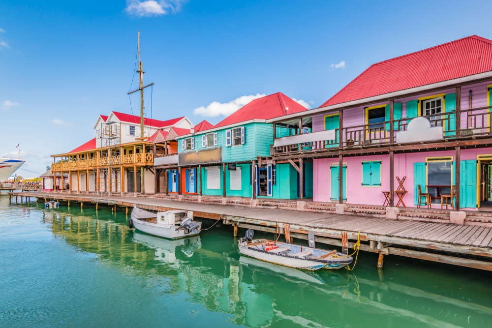 Gorgeous and colorful buildings with red roofs line a boardwalk that also functions as a dock in St. John for a piece on whether or not the Virgin Islands are safe to visit