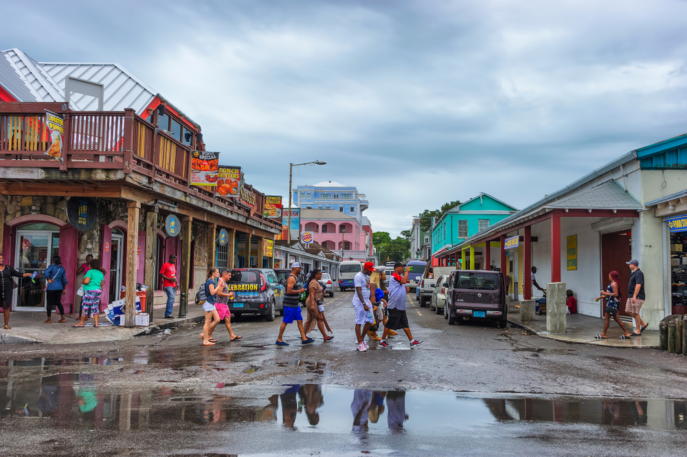 On a gloomy day in Nassau, tourists walk by the camera and toward a puddle of water while wearing shorts, included for a section on the most common crimes that occur in Nassau