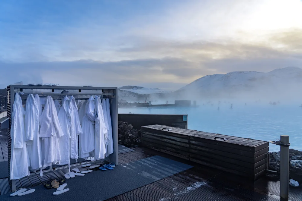 White bathrobes pictured on the side of the thermal baths in blue lagoon in iceland with haze in the background due to evaporation