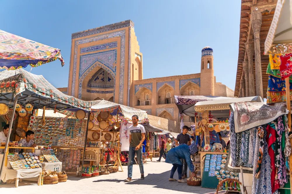 Photo of the famous bazaar street in Khiva pictured with people walking around the market under a bright blue sky
