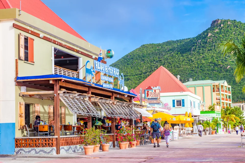 Photo of a crowded street in Philipsburg, Sint Maarten, a very safe place to visit, with lots of little shops below a blue sky