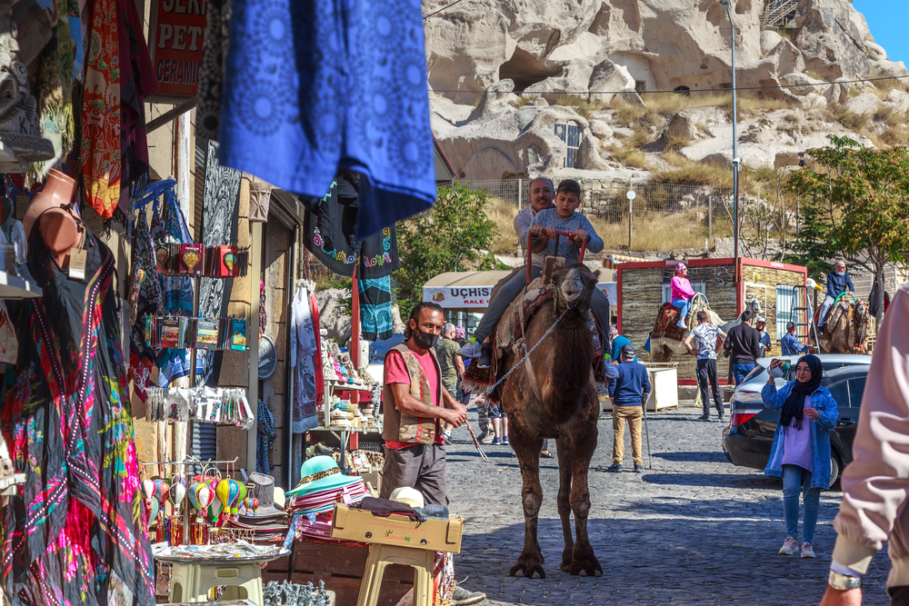 Child riding a camel through the streets of Uchisar for a piece titled Is Cappadocia Safe to Visit