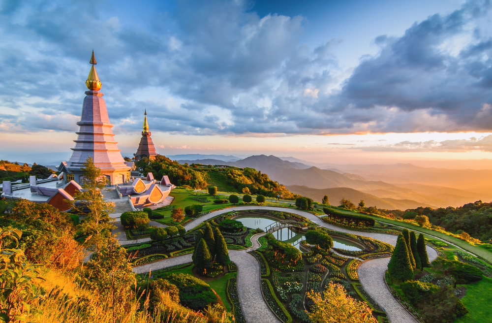 Pictured during the best time to travel to Myanmar, two pagoda are seen overlooking a rolling hillside with winding roads far below