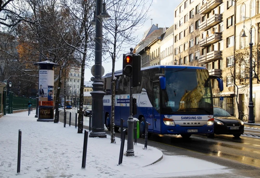 Blue bus and other vehicles drive by the camera in Budapest in Jozsefvaros, one of the least safe areas in Budapest