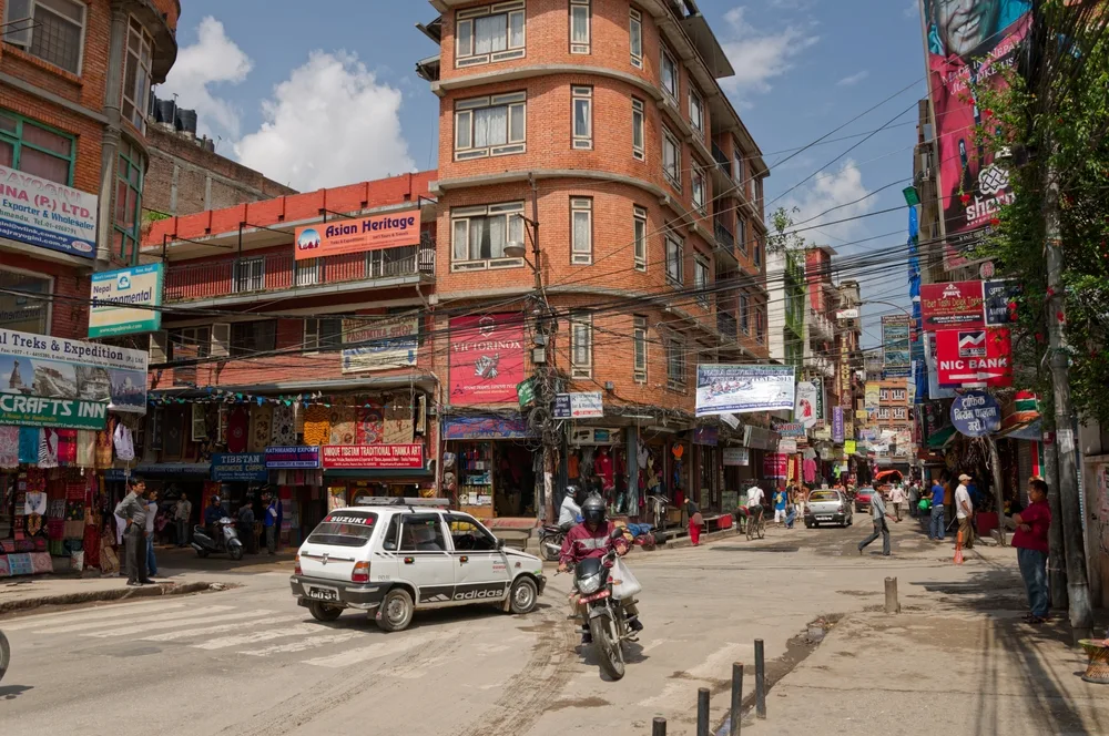 Old-time bustling street in Kathmandu pictured with people and cars making their way around town for a piece on whether or not it's safe to travel to Nepal