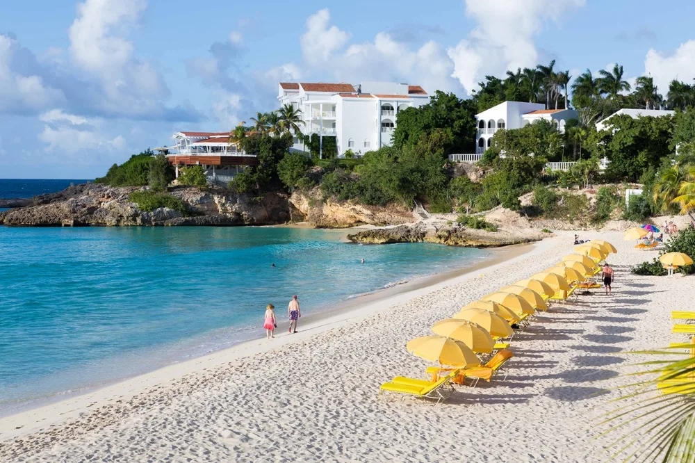 Gorgeous Meads Bay with yellow umbrellas pictured with people walking along the sandy beach