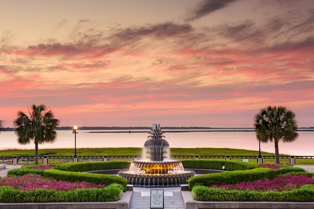 Charleston Waterfront Park seen at sunset with the fountain flanked by palm trees to show why you should visit Charleston