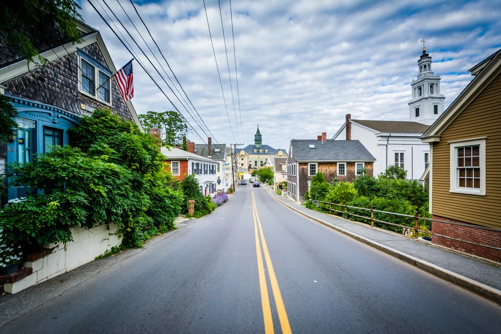 Bradford Street in Provincetown, Cape Cod, pictured during the best time to visit Massachusetts, with shake-sided homes on either side of the idyllic two-lane road
