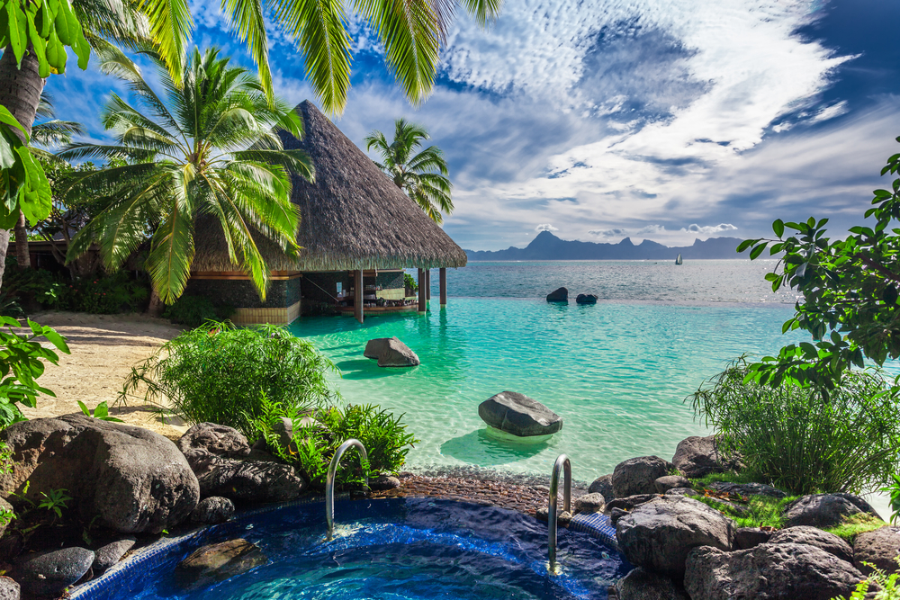 View of a tropical beach resort in Tahiti, a South Pacific island, shown with a jacuzzi and bungalow over the water as a great place to visit on your birthday