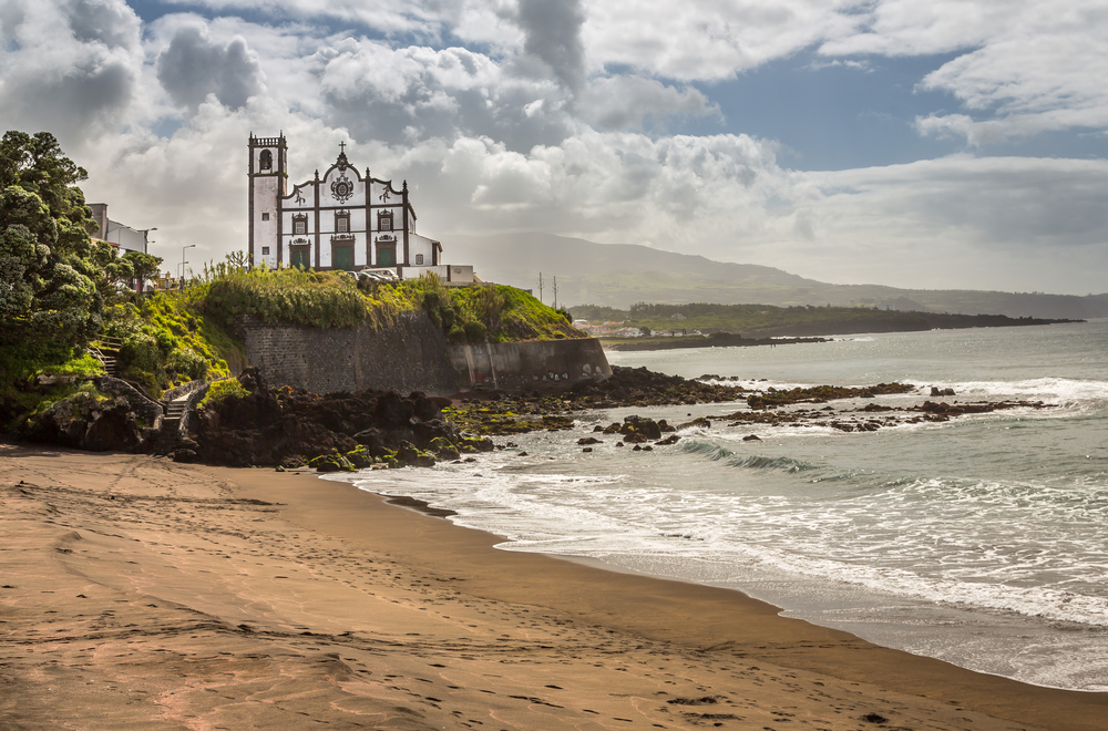 For a guide titled Are the Azores Safe to Visit, a white and brown church above the water near Ponta Delgada