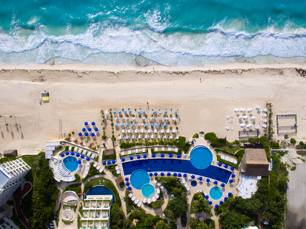 Aerial beachfront view of one of the best adults-only all-inclusive resorts in Cancun seen in the Hotel Zone with pools, beach chairs, and umbrellas