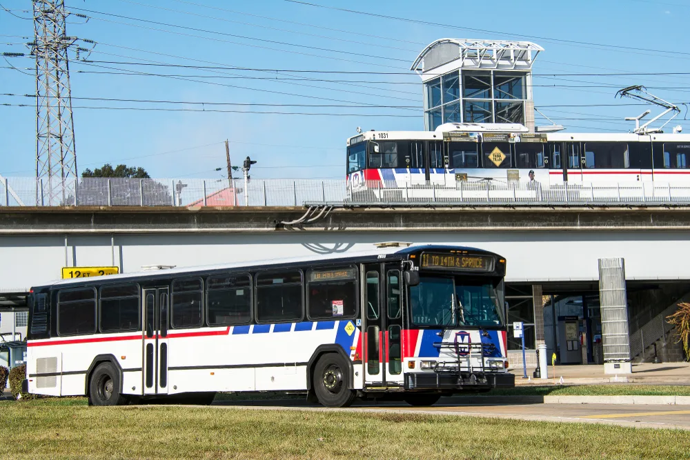 A Metrolink bus and train leaving a station in St. Louis, during the best time to visit, on a nice day