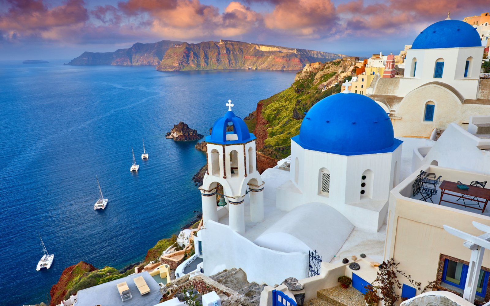 Cliffside town of Fira on Santorini pictured with blue roofs and white walls for a guide to the average trip to Greece cost