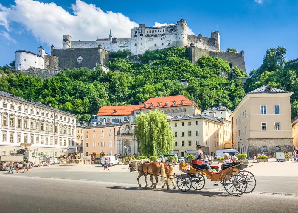 Gorgeous view of a horse-drawn carriage in front of a castle in Salzburg, a top pick for the best areas to stay in Austria