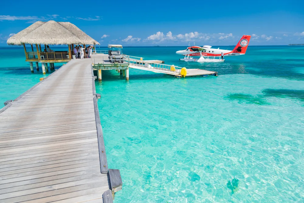 White and red floatplane on the water docking at a resort for a guide to the average Maldives trip cost