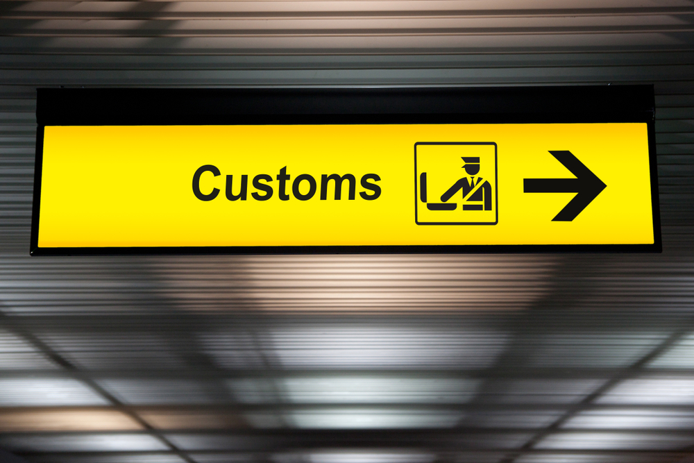 Yellow customs sign at the airport with an arrow directs travelers to CBP officers for an article asking what is customs at the airport?
